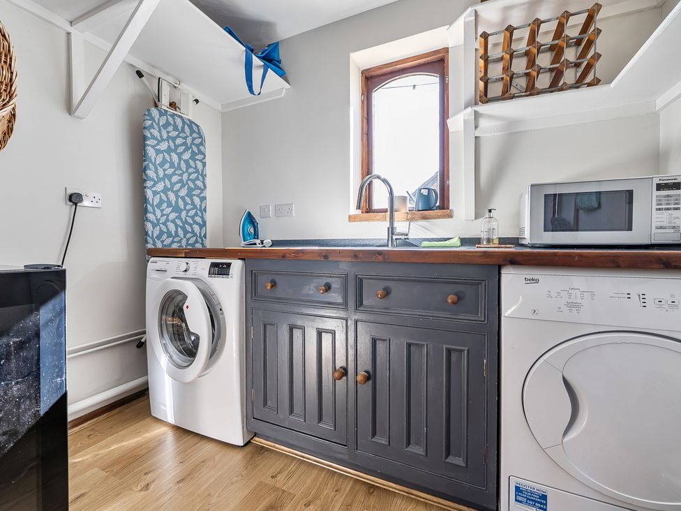 A laundry room with a washing machine, dryer, and kitchen sink at Cutbush Farmhouse Hingham