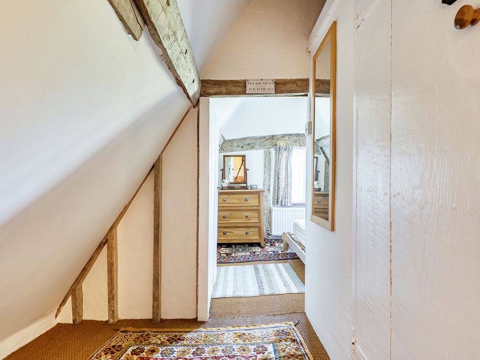 A hallway with a mirror and wooden dresser at Cutbush Farmhouse in Hingham