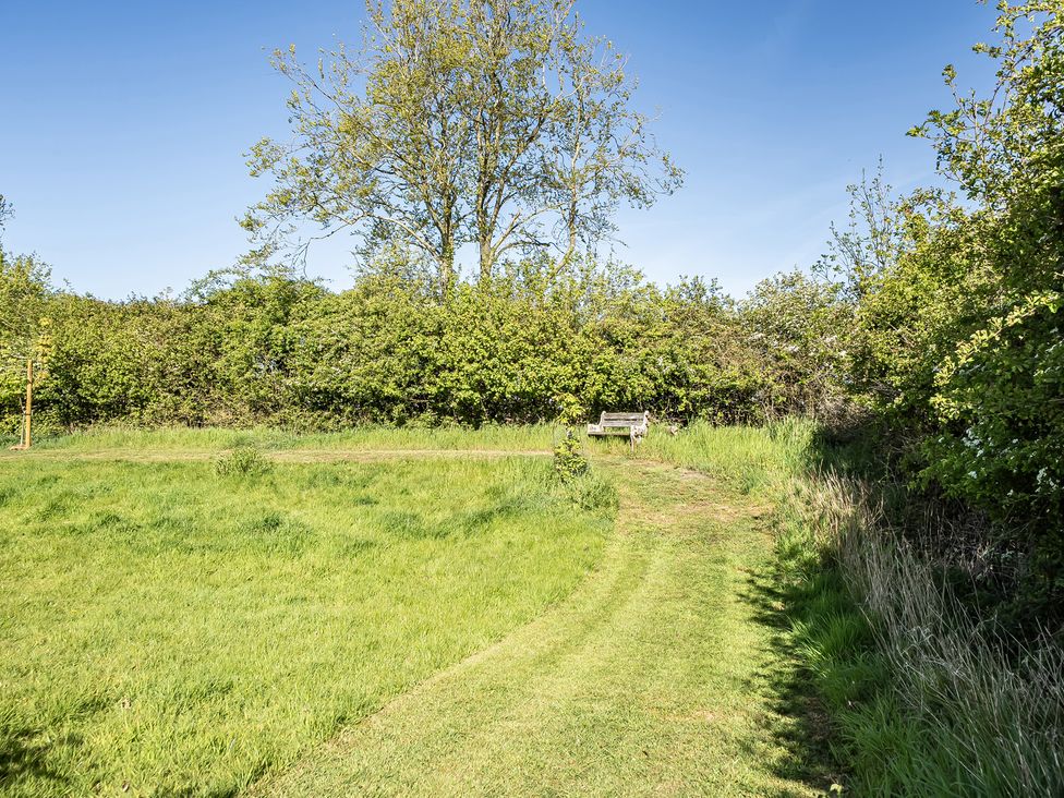 A path leading to a bench with trees and grass at Cutbush Farmhouse in Hingham