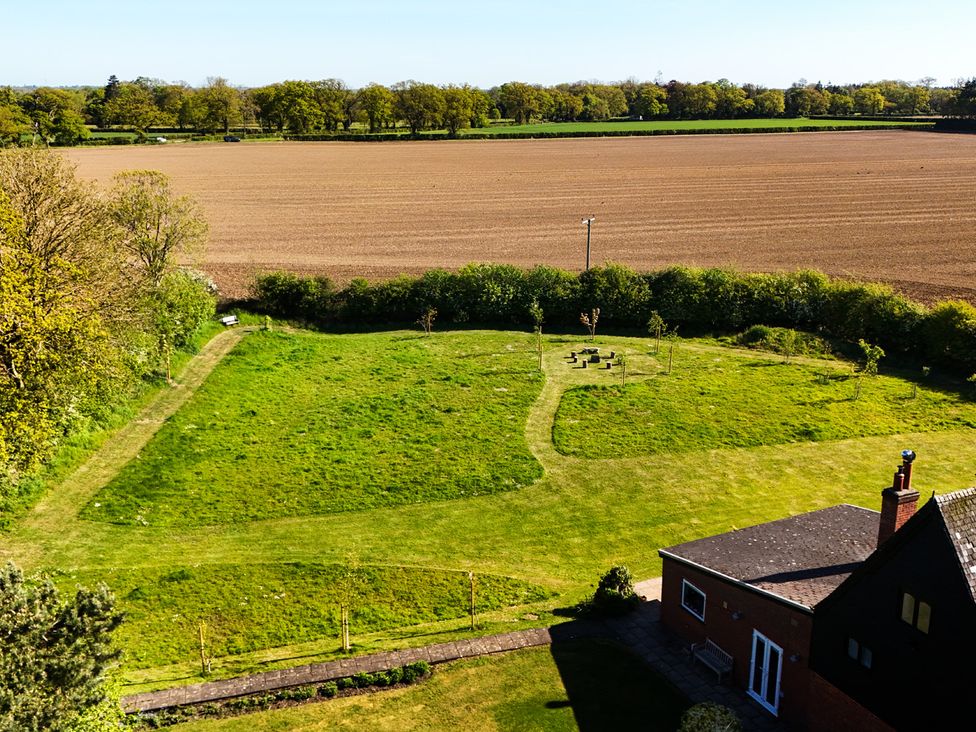 A garden with a house and surrounding fields at Cutbush Farmhouse in Hingham
