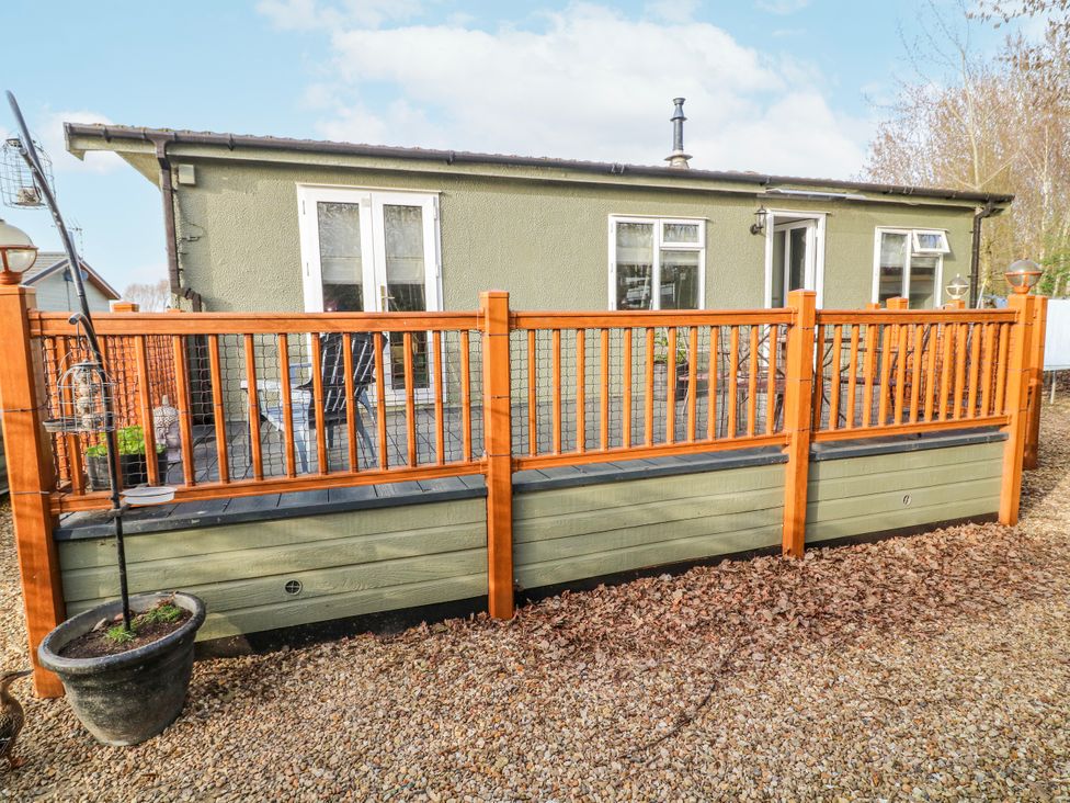 A house with a wooden fence and gravel area at The Nest Lodge 55 Grantham