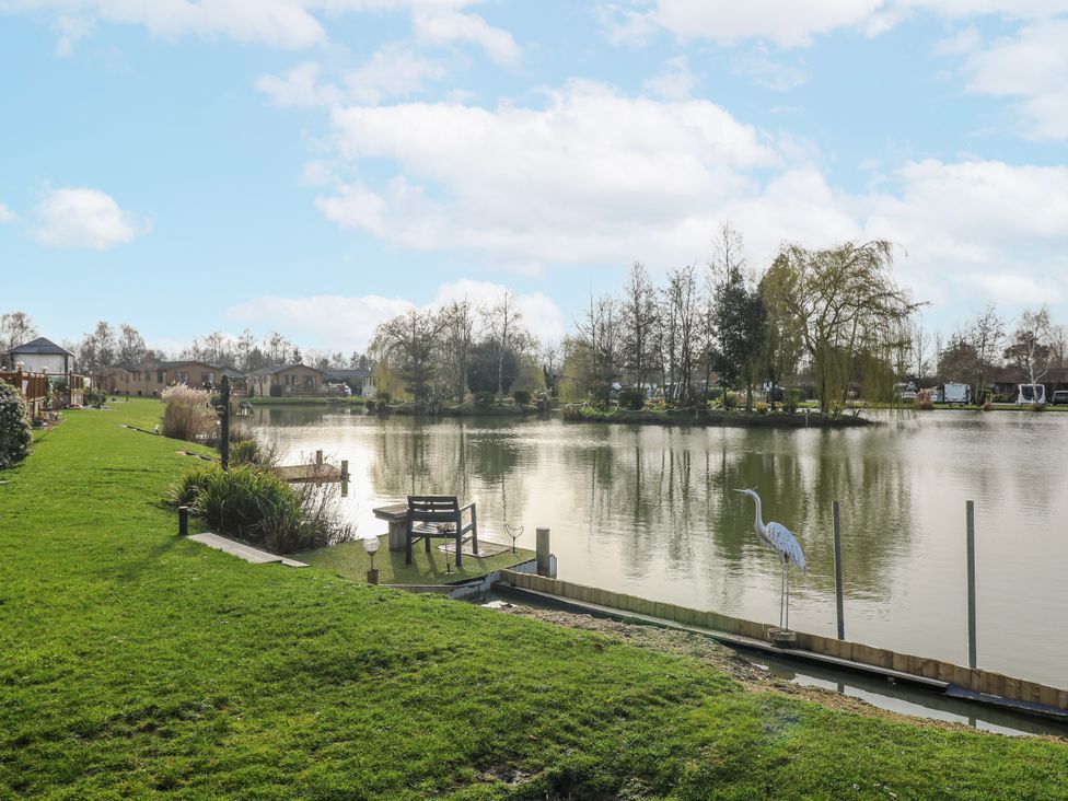 A lake view with grass and a bench at The Nest Lodge 55 Grantham