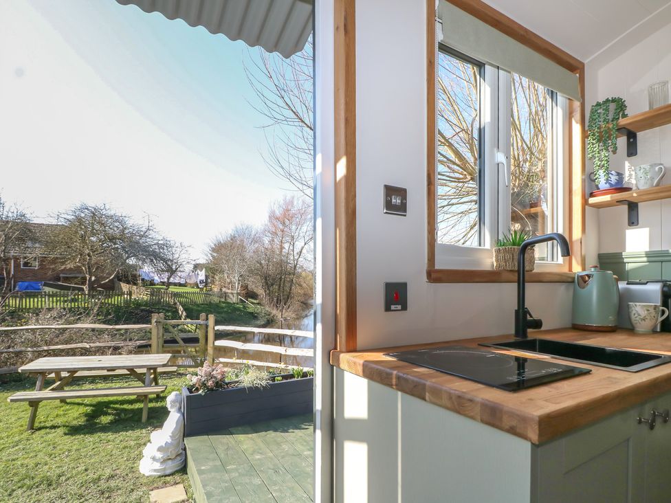A kitchen with a window and stove at Salt Haven Shepards Hut in Pevensey