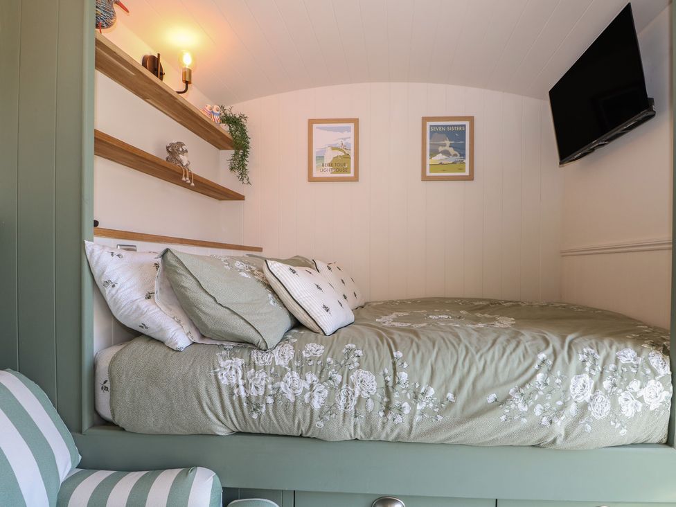 A sleeping area with a bed and shelves at Salt Haven Shepards Hut in Pevensey