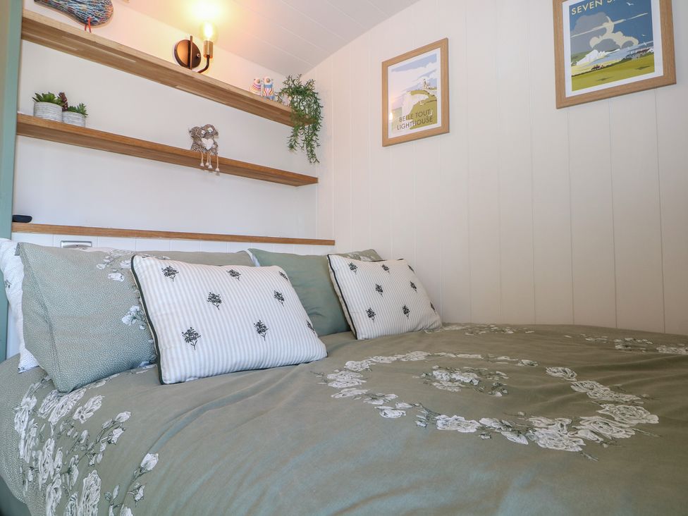 A bedroom with a bed and shelves at Salt Haven Shepards Hut in Pevensey