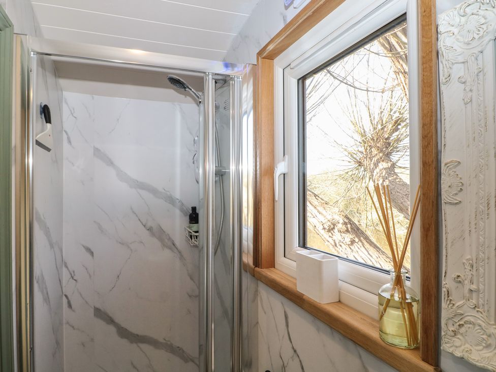 A bathroom with a shower and window at Salt Haven Shepards Hut Pevensey