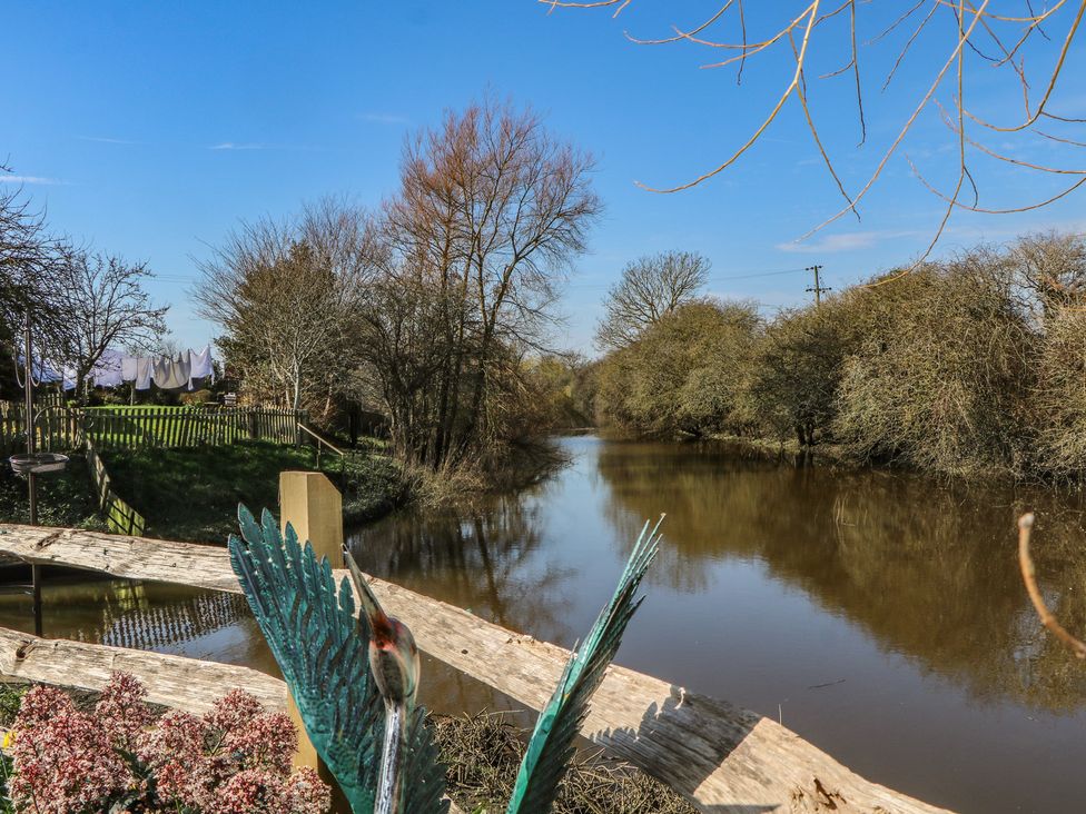 A river surrounded by trees and a fence at Salt Haven Shepards Hut Pevensey