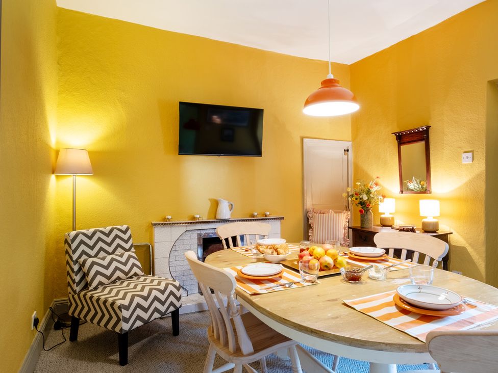 A dining room with a table set and a television at Palace Garden Cottage in Bishop Auckland