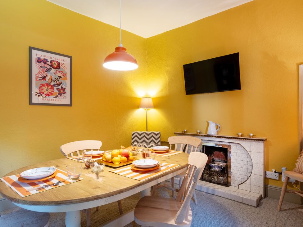 A dining room with a table, chairs, and a television at Palace Garden Cottage in Bishop Auckland