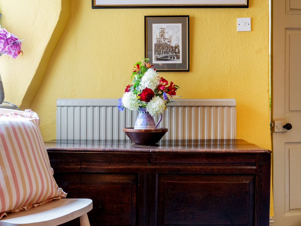 A living room with a table and flower arrangement at Palace Garden Cottage in Bishop Auckland