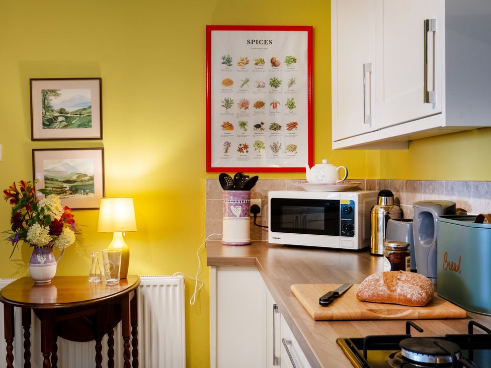 A kitchen with a microwave, teapot, and bread on a counter at Palace Garden Cottage, Bishop Auckland