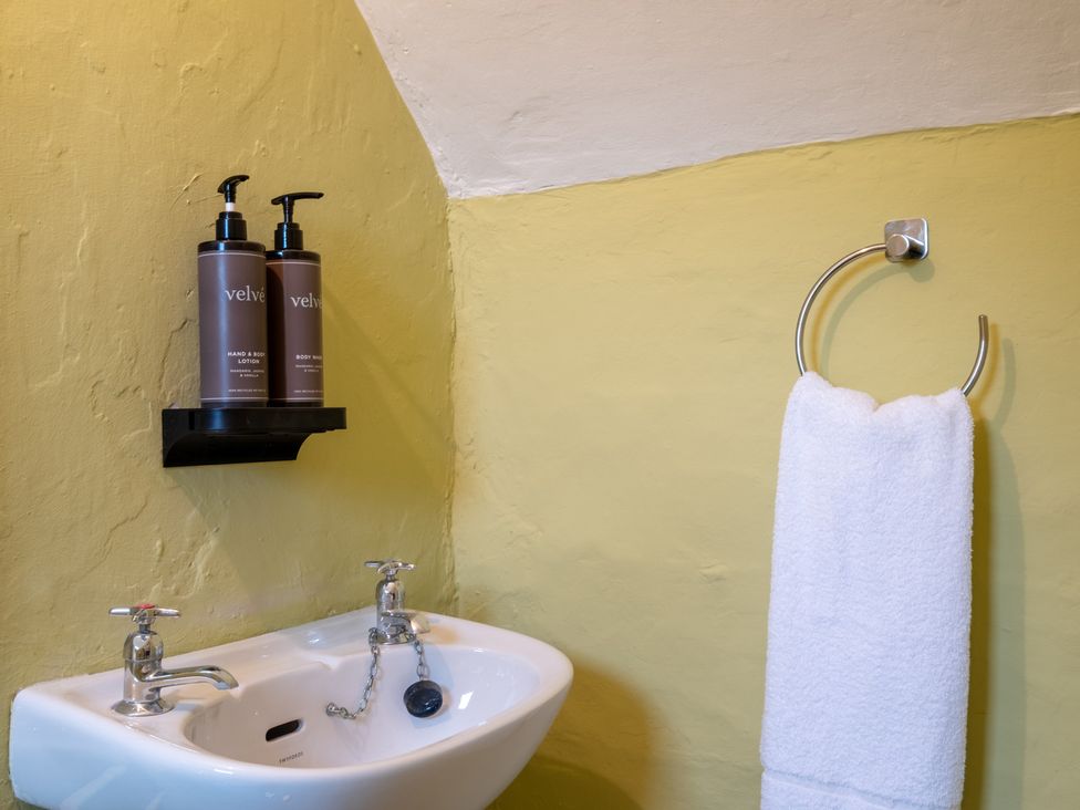 A bathroom with a sink, towel holder, and lotion at Palace Garden Cottage in Bishop Auckland