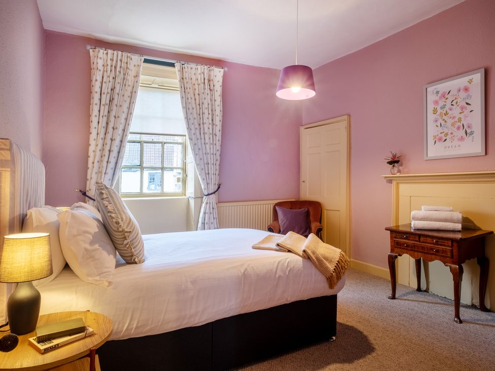 A bedroom with a bed and chair at Palace Garden Cottage in Bishop Auckland