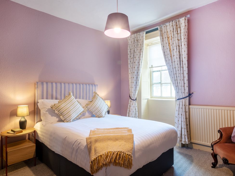 A bedroom with a bed and curtains at Palace Garden Cottage in Bishop Auckland