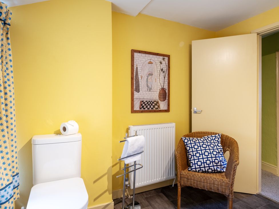 A bathroom with a toilet and a chair at Palace Garden Cottage in Bishop Auckland