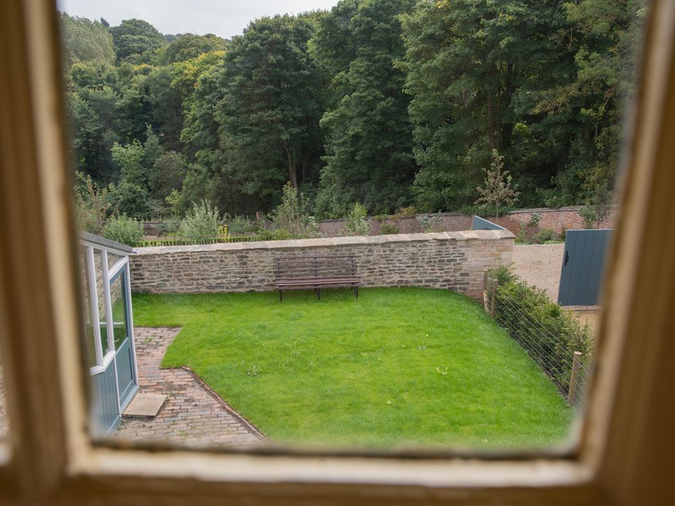 A garden with grass and a bench at Palace Garden Cottage in Bishop Auckland