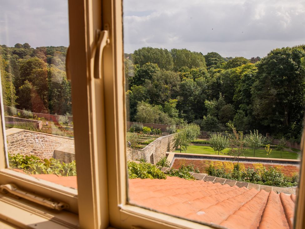 A view of a garden and trees from a window at Palace Garden Cottage in Bishop Auckland