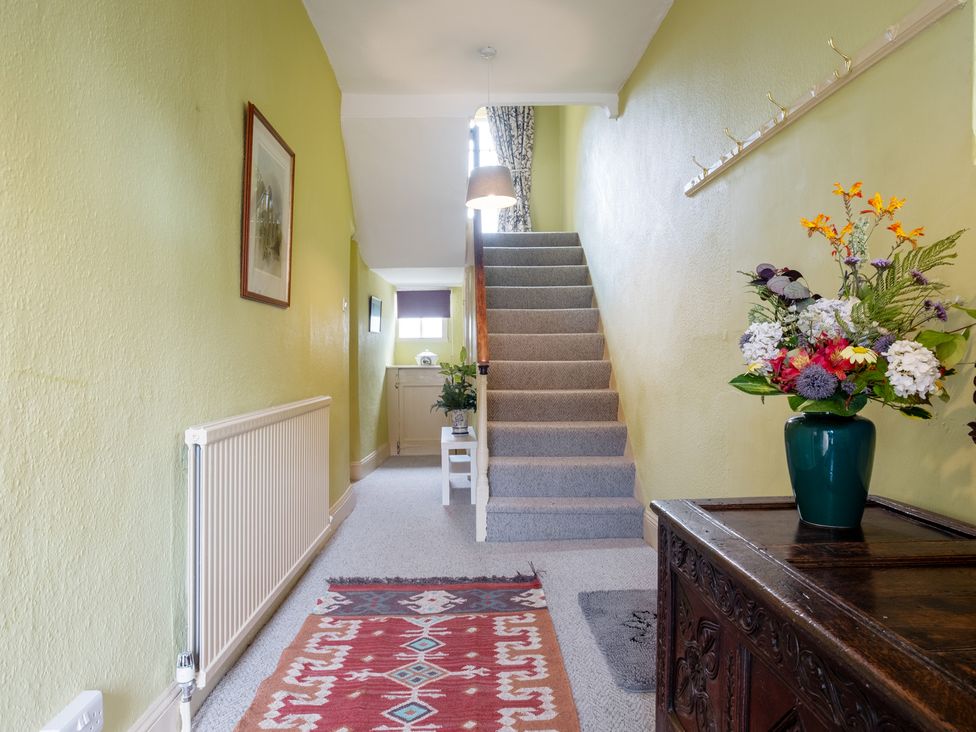 A hallway with a staircase and a flower arrangement at Palace Garden Cottage in Bishop Auckland