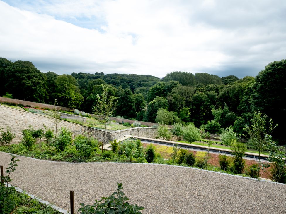 A garden with trees and a gravel path at Palace Garden Cottage in Bishop Auckland