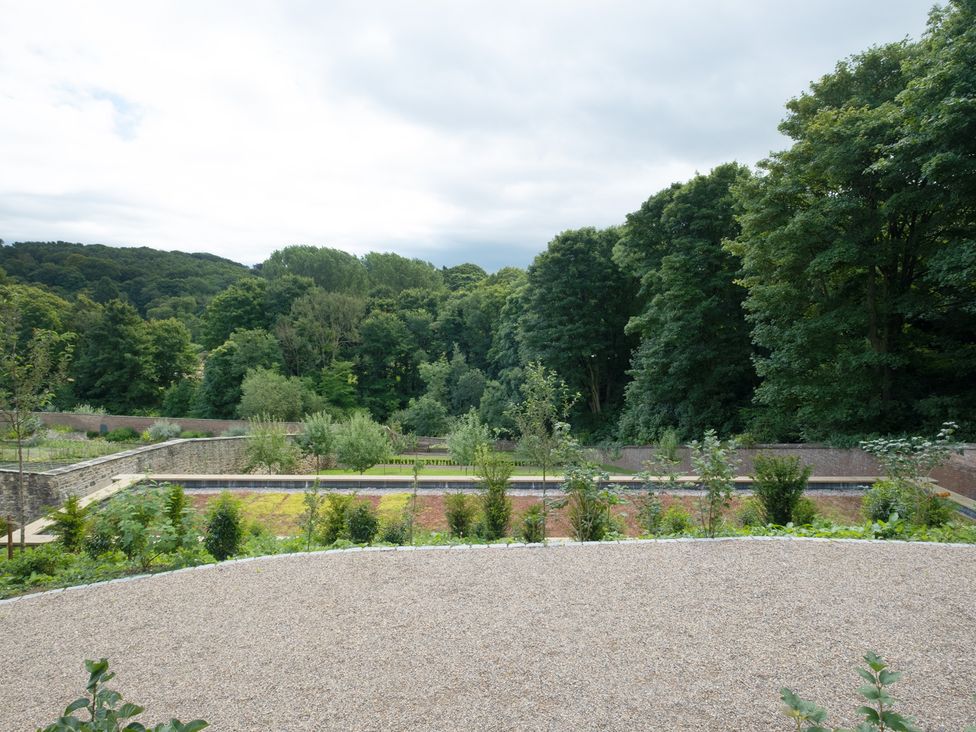 A garden with trees and gravel pathways at Palace Garden Cottage in Bishop Auckland
