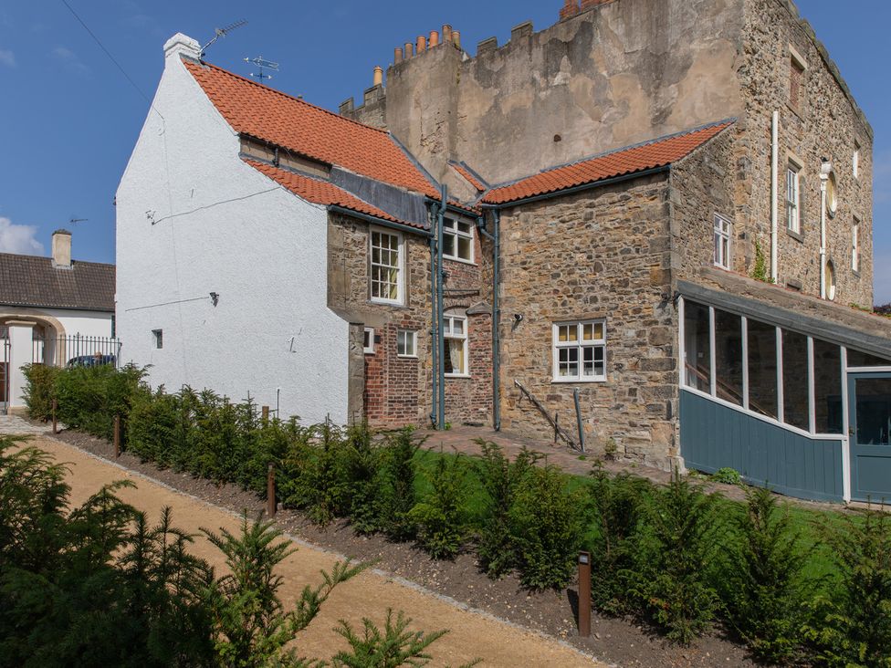 An outdoor view of a building with stone walls and a garden at Palace Garden Cottage in Bishop Auckland