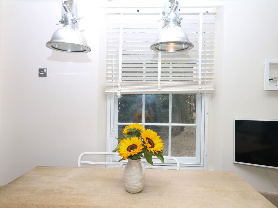 A dining room with a vase of flowers on a table at Dennings House, Mayors Avenue in Dartmouth