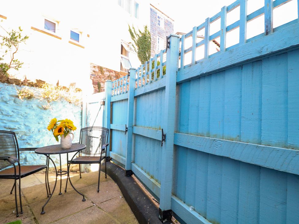 A garden with a blue fence, a table and chairs, and flowers at Dennings House, Mayors Avenue in Dartmouth