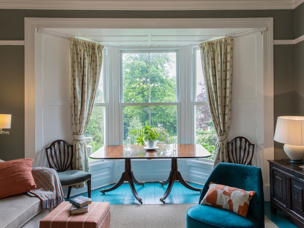 A living room with a table and chairs in front of a bay window at The Clarence in Bishop Auckland