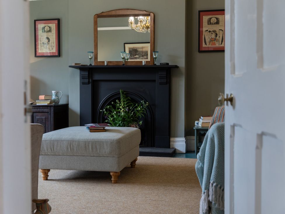 A living room with a fireplace and ottoman at The Clarence in Bishop Auckland