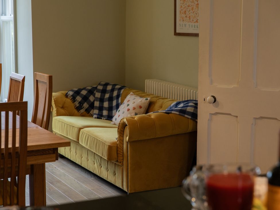 A dining room with a yellow sofa and wooden table at The Clarence in Bishop Auckland