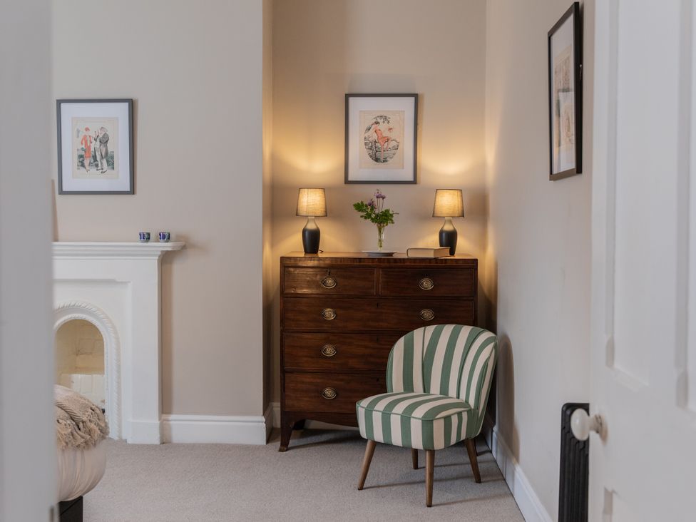 A bedroom with a chest of drawers and a striped chair at The Clarence in Bishop Auckland