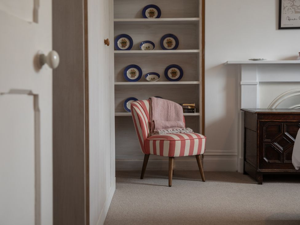 A sitting room with a striped chair and bookshelf at The Clarence in Bishop Auckland