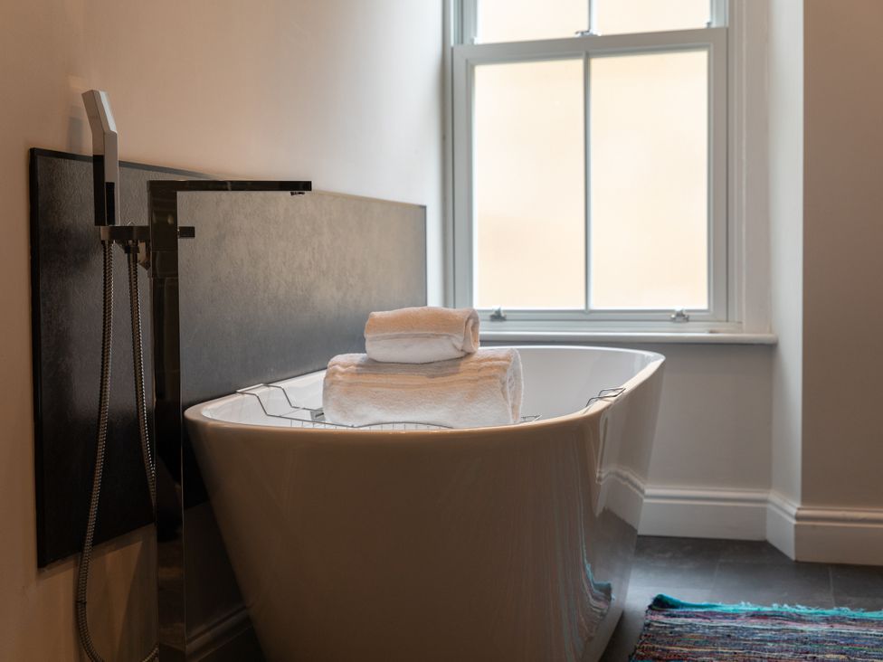 A bathroom with a bathtub and towels stacked on it at The Clarence in Bishop Auckland