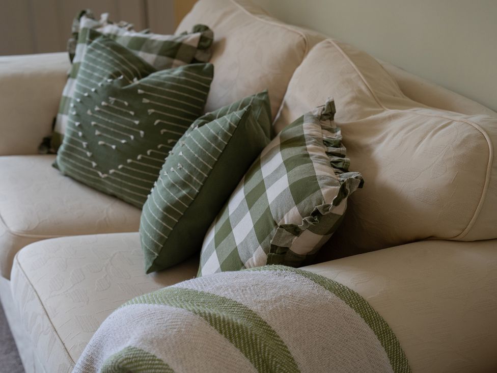 A couch with green pillows and a blanket at Churchill Cottage in Bishop Auckland