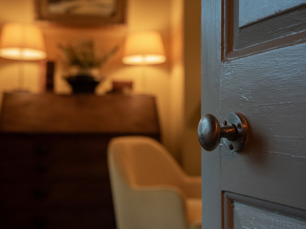 A door with a doorknob leading into a room with lamps and furniture at Churchill Cottage Bishop Auckland