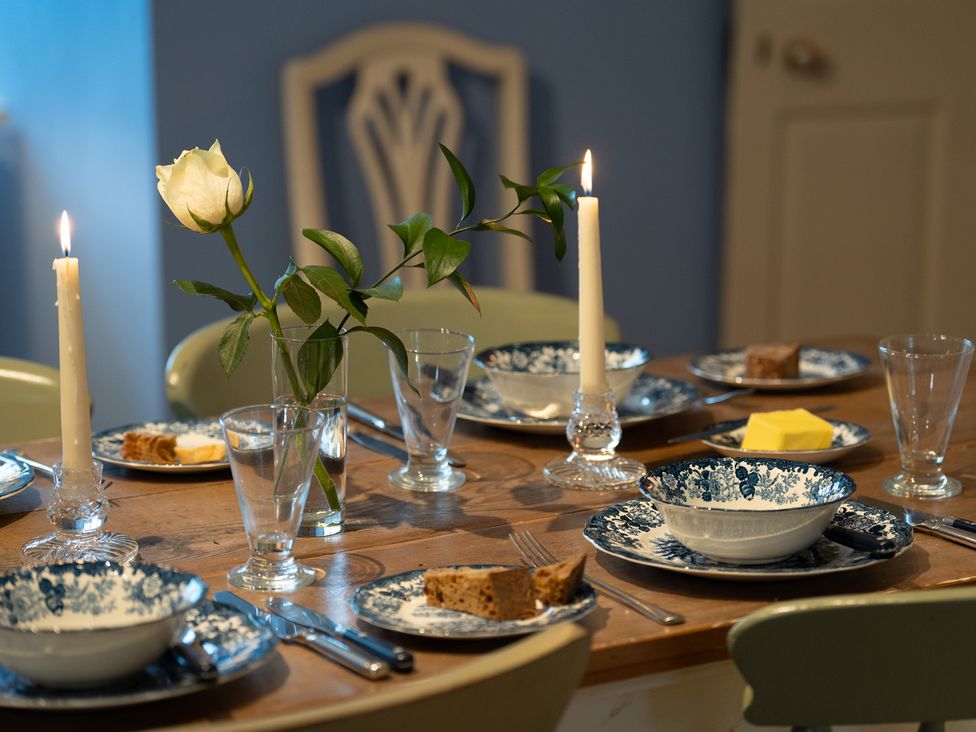 A dining room table set with plates, candles and a rose at Churchill Cottage in Bishop Auckland