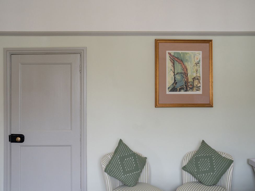 A sitting room with a door and a painting above a chair at Churchill Cottage in Bishop Auckland