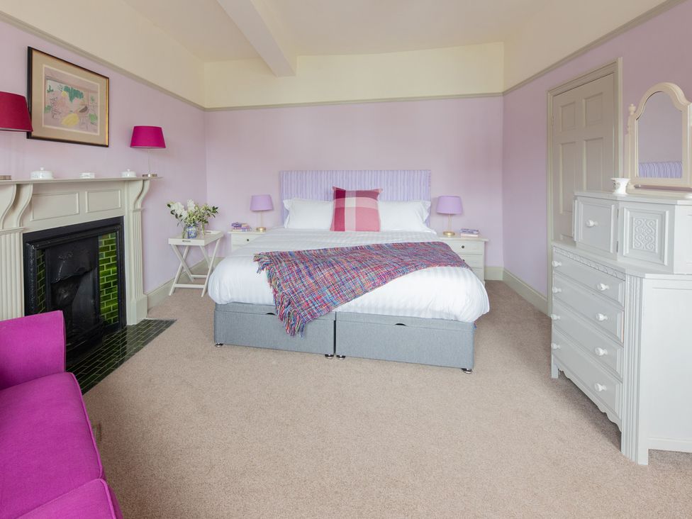 A bedroom with a bed, armchair, and a fireplace at Churchill Cottage in Bishop Auckland