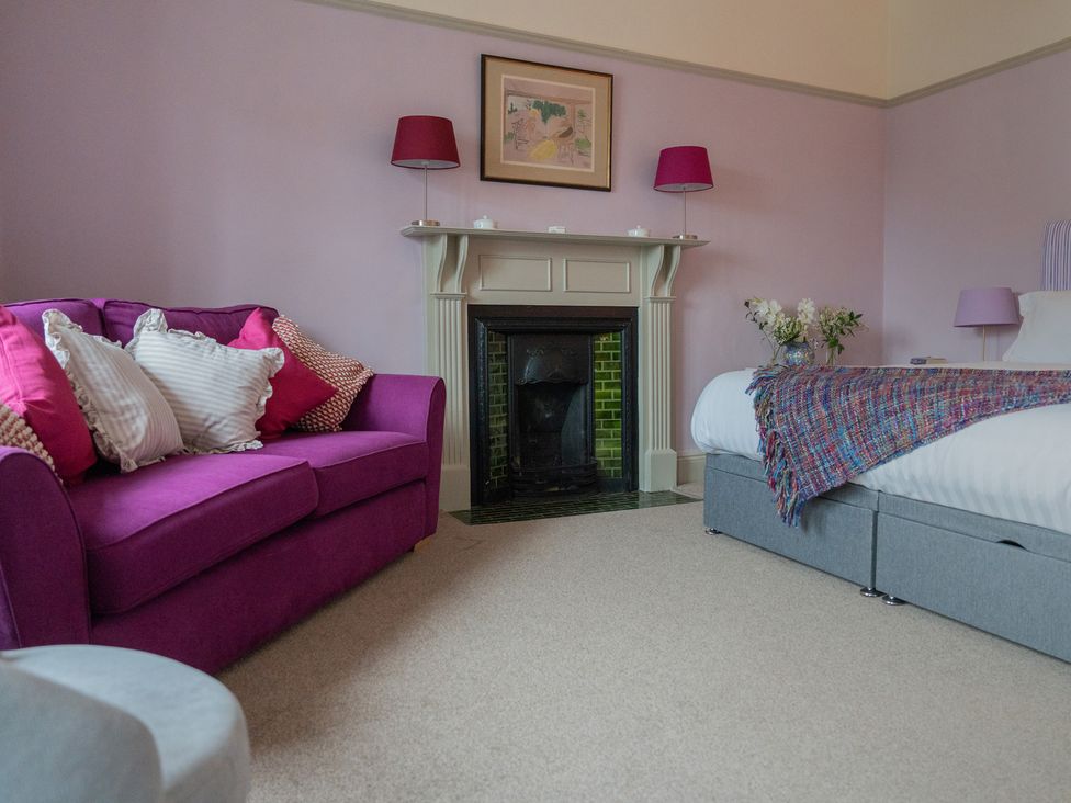 A bedroom with a purple sofa and a fireplace at Churchill Cottage in Bishop Auckland