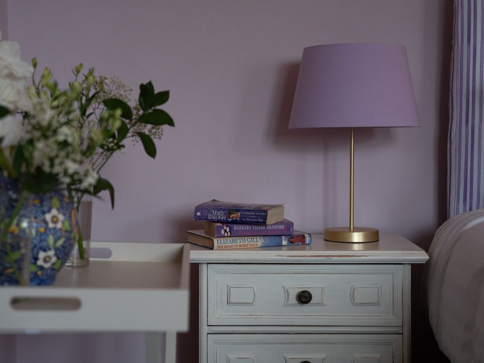 A bedroom with a nightstand and books at Churchill Cottage in Bishop Auckland