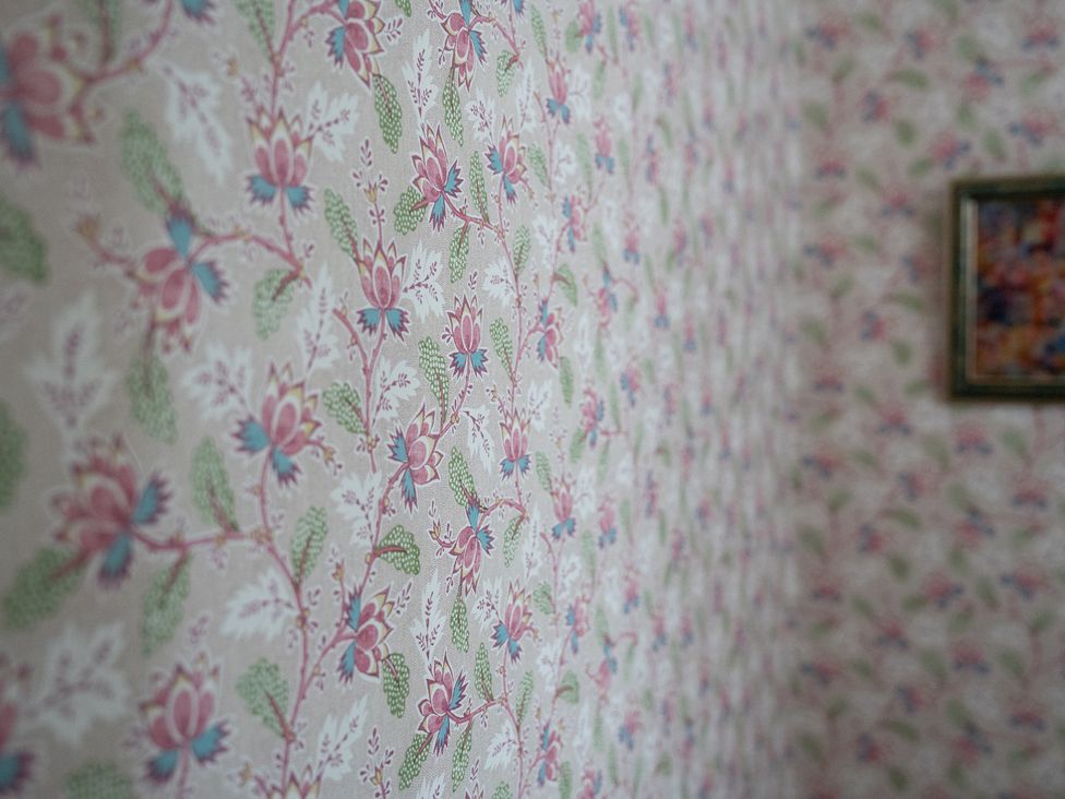 A wall with floral wallpaper and a framed picture at Churchill Cottage in Bishop Auckland