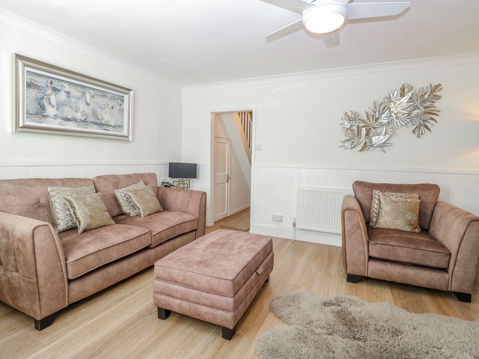 A living room with a sofa, armchair, and ottoman at 17 Woodside Avenue, King's Lynn
