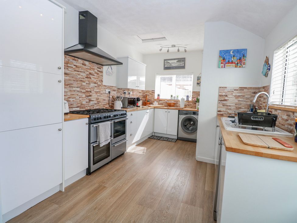 A kitchen with stove, washing machine, and cabinets at 17 Woodside Avenue in King's Lynn