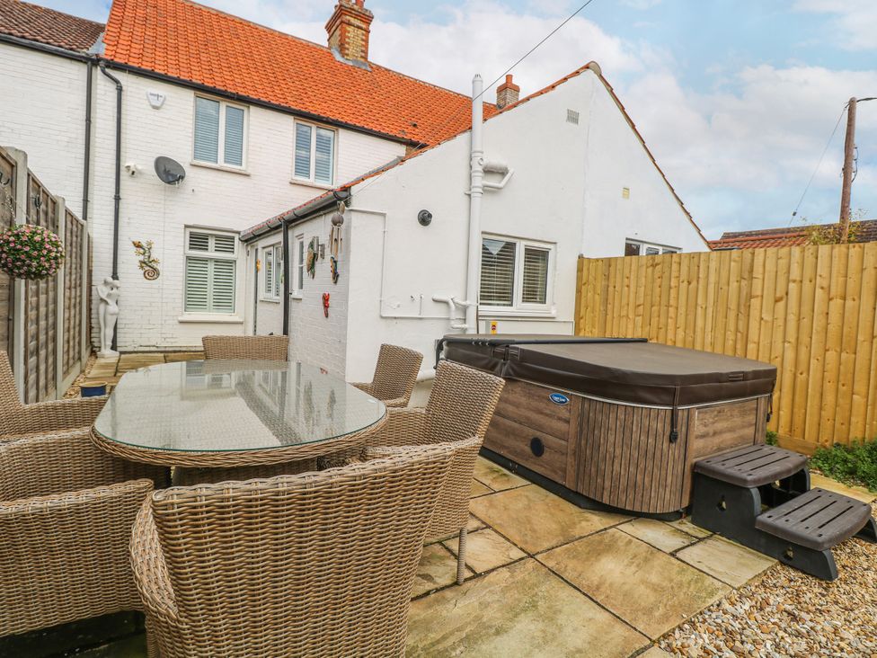 A garden with a table and chairs next to a hot tub at 17 Woodside Avenue in King's Lynn