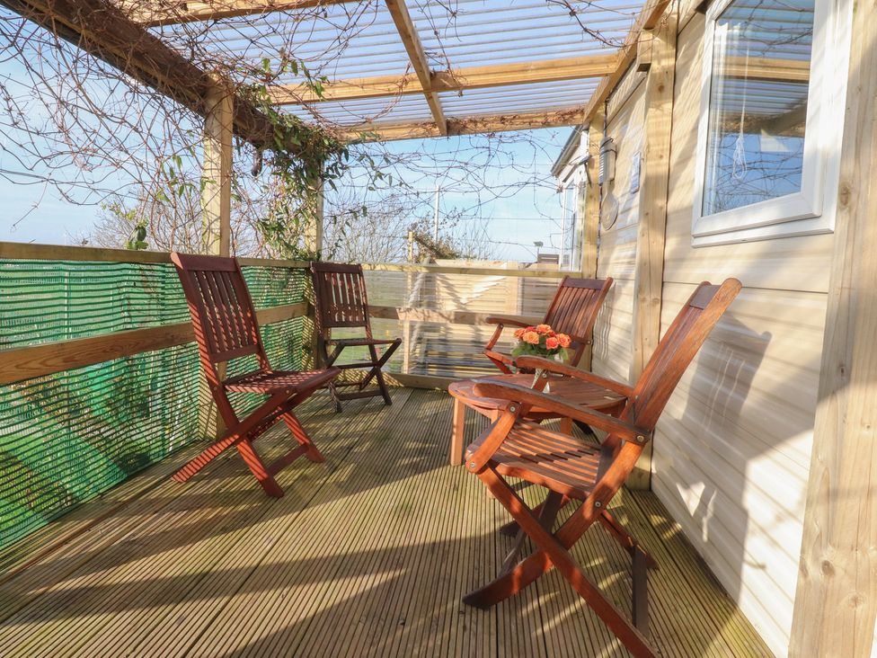 An outdoor space with wooden chairs and a table at Cornholme Lodge in Accrington