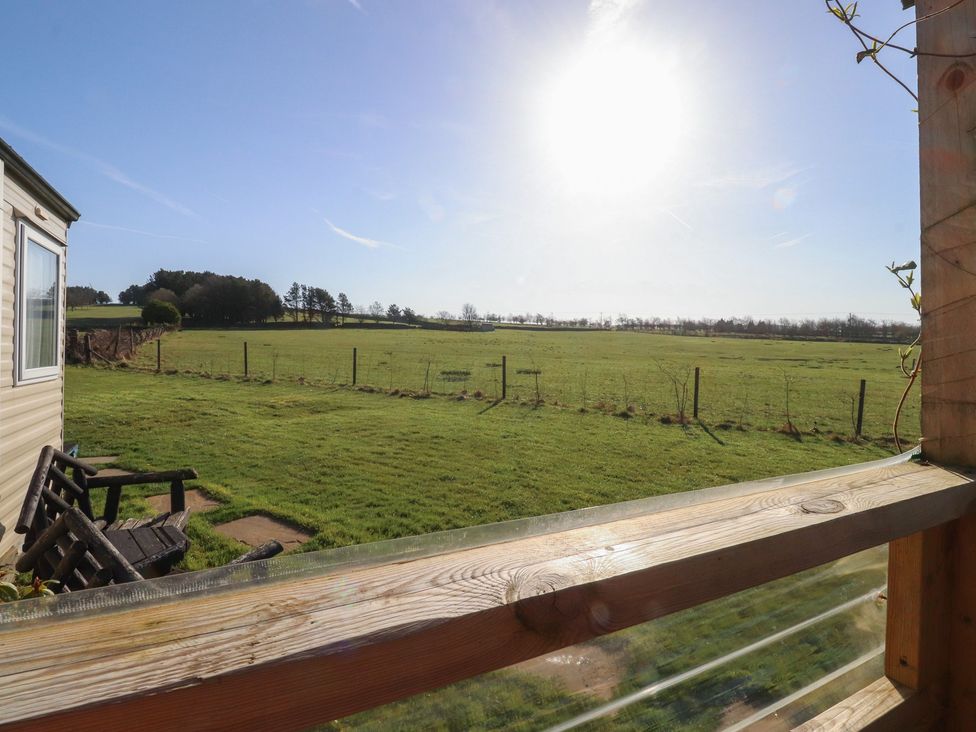 A view of a grassy field with a chair on the balcony at Cornholme Lodge Accrington