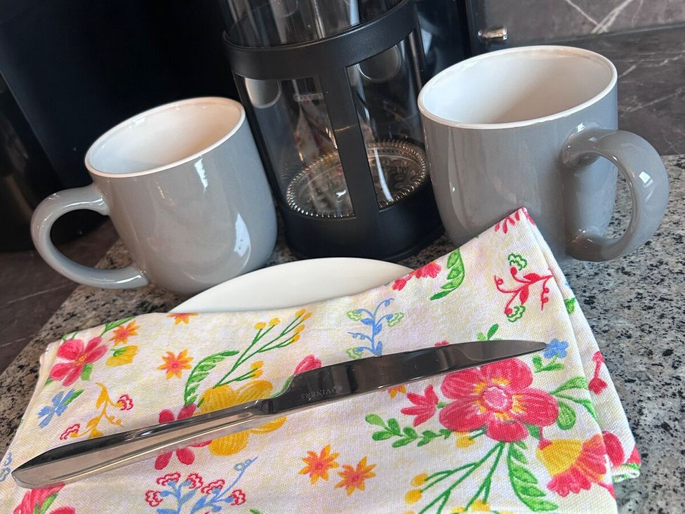 Kitchen scene with mugs, a knife, a plate, and a patterned napkin at 3 Linshader Stornoway