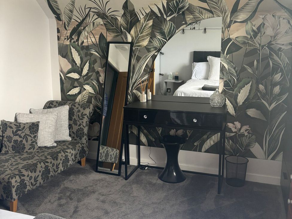 A bedroom with a mirror and table at 3 Linshader in Stornoway