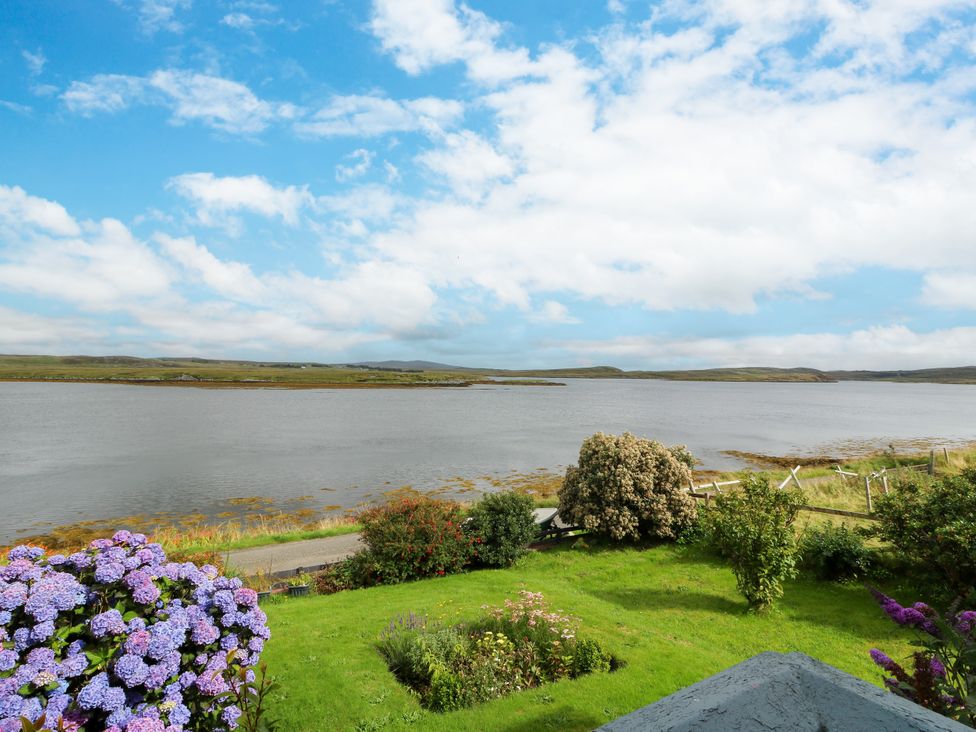 A view of water, flowers, and grass at 3 Linshader in Stornoway