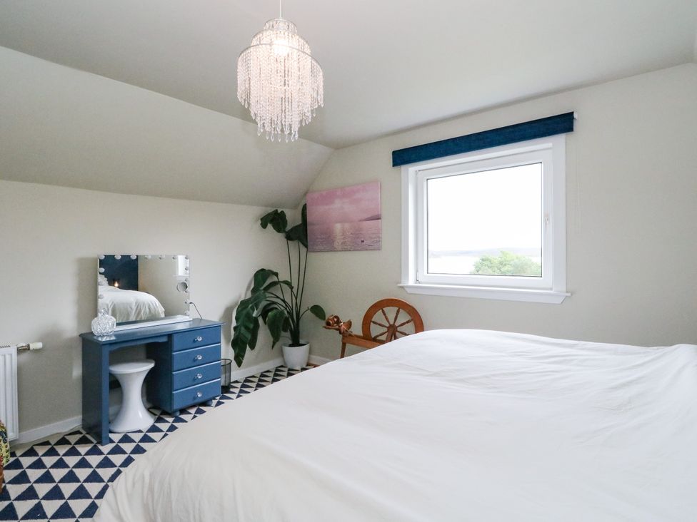 A bedroom with a bed and a desk under a window at 3 Linshader Stornoway